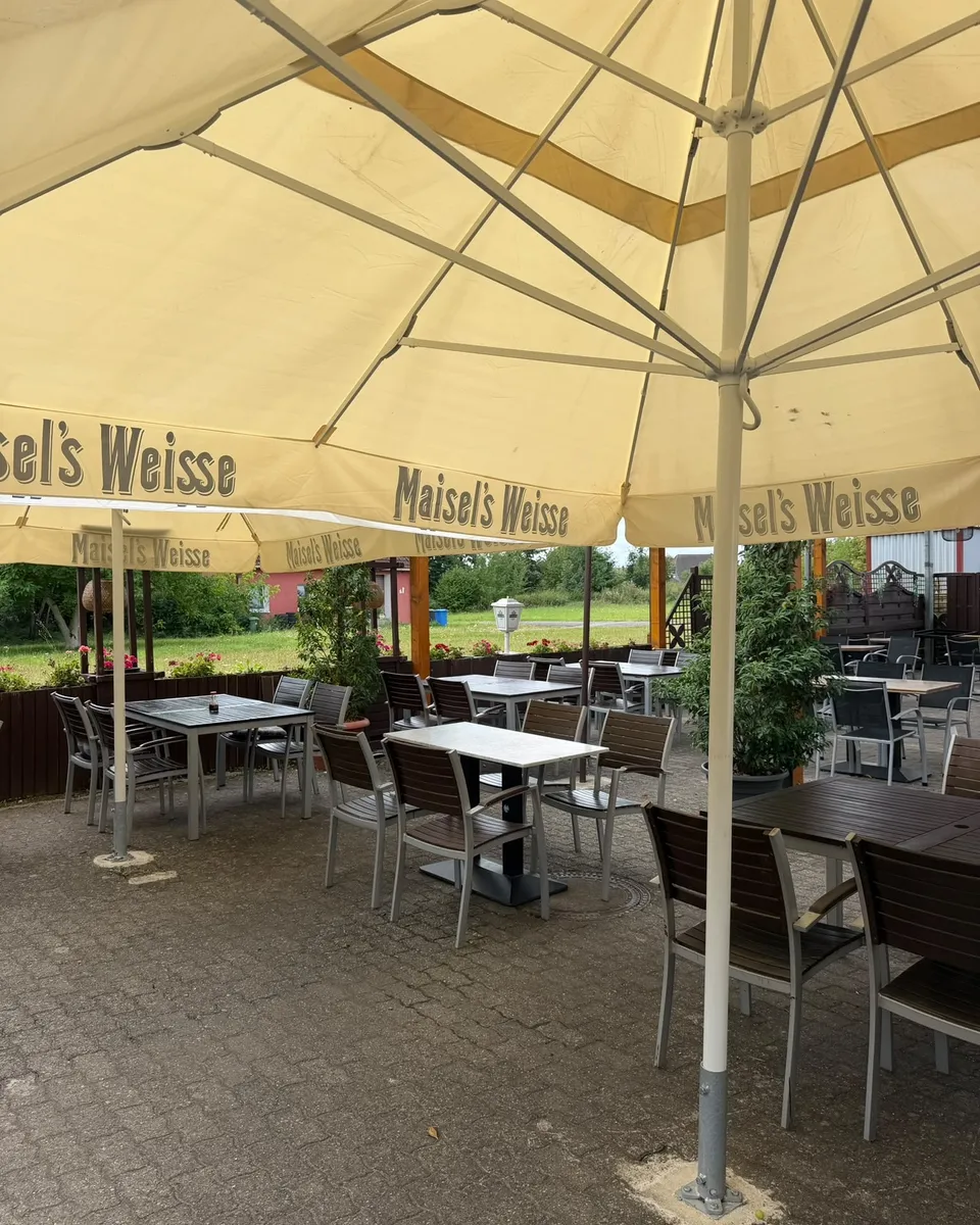 Terrasse bei Musuko mit mehreren Tischgruppen und Sonnenschirmen für größere Runden